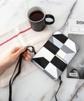 Super Chic Black And White Piano Grid Phone Pouch With Adjustable Crossbody Strap Hella Protective Lightweight Cell Phone Purse on a table with coffee.