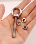 Hand holding 10 Pack M6 x 50mm Eyebolts With Nuts And Washers, Stainless Steel Marine Grade Shoulder Eye Bolts for outdoor projects.