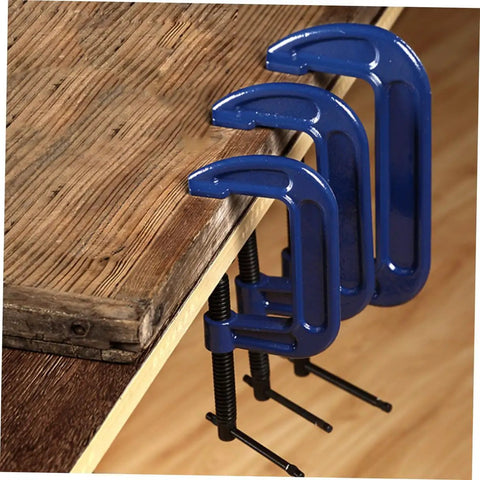 Three sizes of blue woodworking G clamps with quick release C clamp for desk mounting, secured on wooden tabletop.