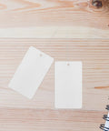 Blank White PVC Hanging Tags With Lanyard Waterproof 100 Pcs Jewelry Display Labels on a wooden surface