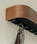 Side view of walnut wall mounted key holder with wooden shelf, showing six slick hidden hooks for keys.