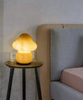 Desert Swirl Mushroom Lamp With Stepless Dimmable Glass Shade on bedside table by bed, warm white LED bulb glowing