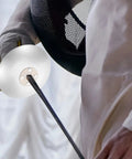 Close-up of a fencer holding a foil with guard, wearing competition gear. Fencing Accessories Set With Foil Guard And Hand Pads.