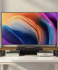 Heavy Duty Dual Monitor Stand Riser in wood and steel with rustic brown finish, shown with TV on white desk