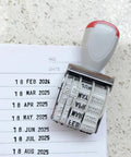 Totally Versatile Rubber Date Stamp With Rotating Mechanism For Scrapbooking And Office Tasks on paper with marked dates.