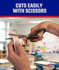 Hands using scissors to cut Roll N Cut Flexible Magnetic Tape Refill With Crazy Sticky Adhesive Backing One Sixteenth Inch Thick
