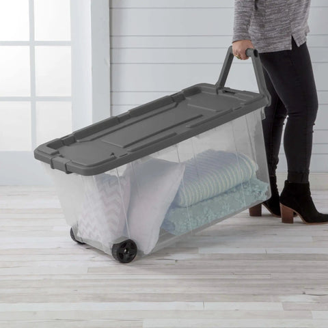 Rugged Pull Along 160 Quart Rolling Storage Tote With Transparent Bottom carrying blankets and pillows on wheels.