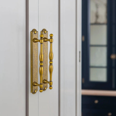 Gotta Have These Antique Brass Cabinet Pulls 2 Pack Featuring Classic Turned Spindle Shape And Chunky Decorative Backplate on cabinet door