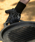 High Heat Grill Gloves For Cooking And BBQ, Oven Mitts With Universal Fit, Non Slip Grip, holding a black grill