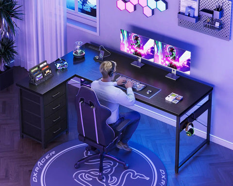 Person gaming at L Shaped Gaming Desk With Four Drawers And Power Outlets For Home Office 61 Inch Corner Desk With USB Charging Port And Host Stand Dual Monitor Ready Reversible Layout Easy To Assemble Black