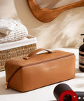 Travel Hair Tool Case For Dyson Airwrap And Shark FlexStyle, brown PU leather, on table near hair products and mirror.