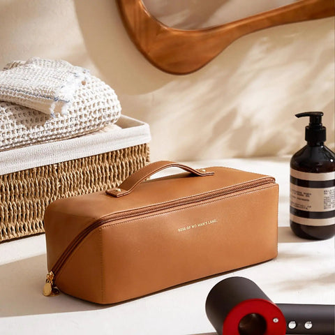 Travel Hair Tool Case For Dyson Airwrap And Shark FlexStyle, brown PU leather, on table near hair products and mirror.