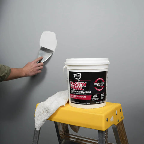 Applying Fast N Final Lightweight Spackling Patch And Prime In One Step For Walls White Gallon Ultra Smooth Finish on wall using spatula