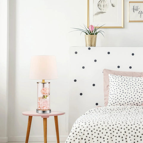 Maya 21 Inch Fillable Table Lamp With Clear Glass Base And White Linen Shade on a wooden bedside table beside polka dot bedding