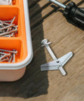 Top Shelf 30 Piece Carbon Steel Drywall Anchors M5 X 60mm Butterfly Toggles on a wooden surface with screws and a screwdriver.