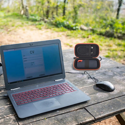 Laptop on wooden table beside open Hard Case For SanDisk Extreme Portable SSD Built Tough Rugged Foam Padding And Mesh Pocket.