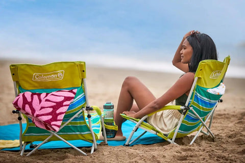 Person relaxing on beach in Utopia Breeze Lightweight Beach Chair With Cup Holder And Carry Bag For Easy Outdoor Relaxation.