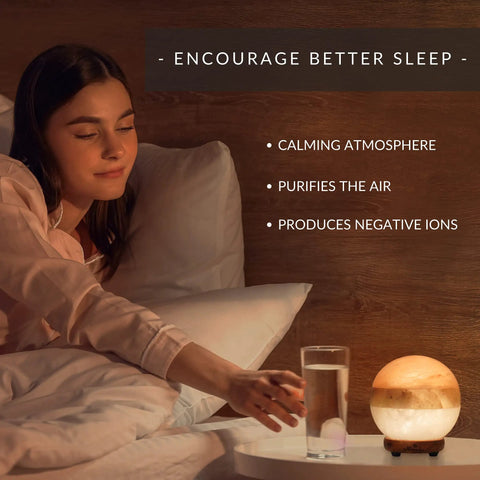 Dual Illumination Himalayan Salt Lamp Round Globe on wooden stand in cozy bedroom at night.