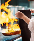 Person holding Tough As Nails Heavy Duty High Temp Carbon Felt Welding Blanket 6mm Thick in front of flames in kitchen