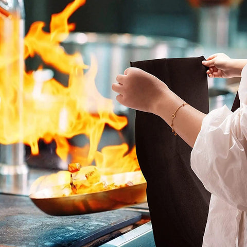 Person holding Tough As Nails Heavy Duty High Temp Carbon Felt Welding Blanket 6mm Thick in front of flames in kitchen