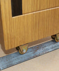V-Type groove wheel caster with bracket, pack of 2; brass-colored metal, installed under wooden cabinet on metal track