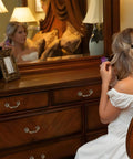 Woman sitting at wooden dresser with antique drop bail drawer pulls in bronzed finish, mirror reflection, bedroom setting