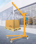 Heavy Duty Electric Engine Hoist With Mobile Wheels For Indoor Workshop Lifts Foldable Steel Crane Handling Massive Loads Up To Five Hundred Kilograms lifting a cardboard box on a pallet in a warehouse.
