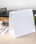 Sturdy White Paper Shopping Bags With Handles 14.2 By 8.3 By 13.2 Inches 100 Pack Durable Grocery Gift Bags on a table with takeout items.