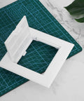 Sleek 3X3 Inch White Drywall Access Panel For Bathroom Plumbing Maintenance Durable Pvc Wall Cover Plate on green cutting mat.