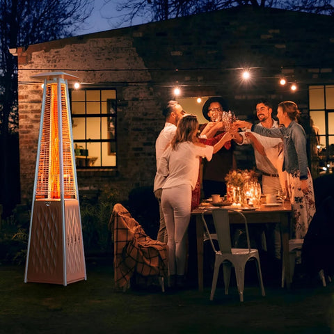 IDEASURE patio propane heater tower with white finish, glowing flame at outdoor dinner party scene