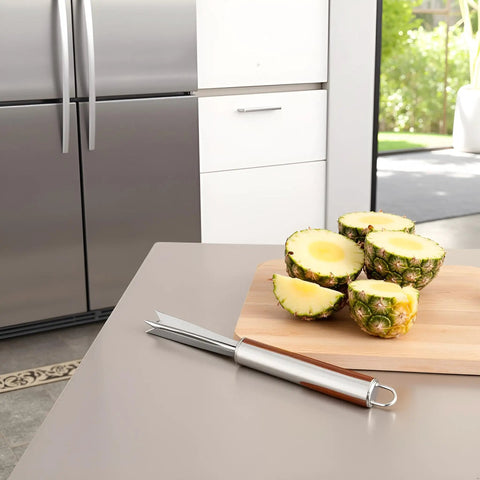 V Shape Pineapple Eye Remover Tool With Multipurpose Clip Stainless Steel Peeler next to sliced pineapples on kitchen counter