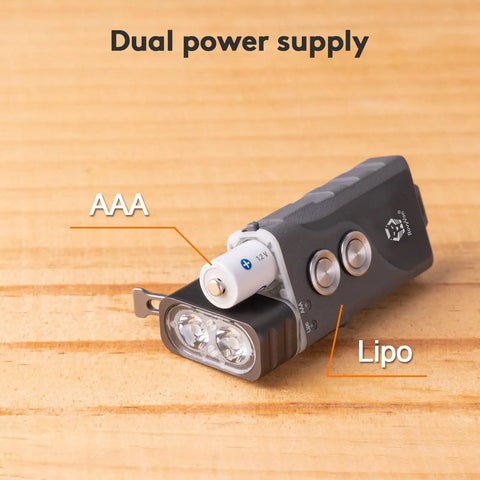 EDC Keychain Flashlight with dual power AAA battery and LiPo system, showcasing compact design on wooden surface.