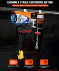 Front view of orange electric hoist winch mounted to a ceiling beam with wired yellow remote and hook