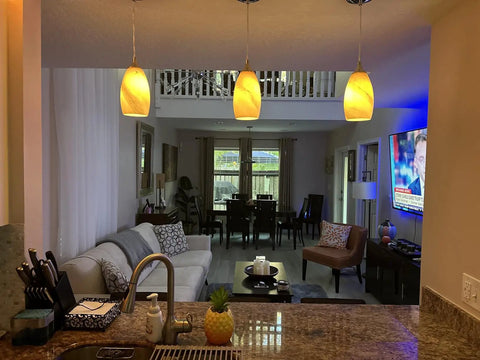 Three Pack Indoor Mini Pendant Lights For Kitchen Island In Polished Nickel With Hand Blown Orange Glass Shades 4.75 Inch Fully Dimmable UL Listed Sweet Bar Counter Dining Room Accent Lighting hanging over a kitchen island, illuminating a modern living space.