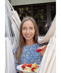 Woman enjoying fruit in Heavy Duty Hammock Chair With Two Cushions And Protective Waterproof Cover For Indoor And Outdoor Relaxation.
