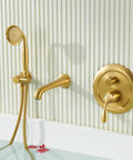 Gold wall-mounted tub filler with hand shower set against a striped background.