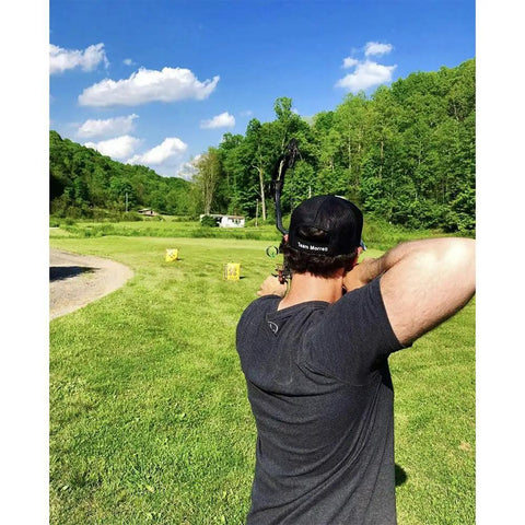 Man aiming at Yellow Jacket Stinger Field Point Archery Target Bag With Dual Sides And Ten Bullseyes in a grassy field