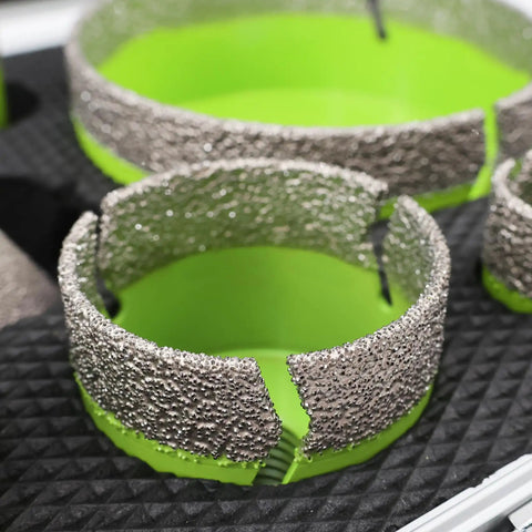 Close-up of Porcelain Tile Diamond Core Drill Bit Set and Hole Saw Kit, textured edge detail, green interior on black mat.
