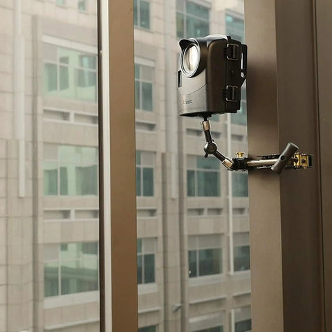 Hella Rugged Construction Time Lapse Camera Bundle With 1080p Waterproof Housing mounted on a window with a clamping setup.