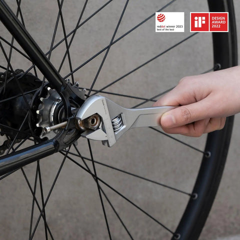 Hand using wrench on bike wheel, showcasing practical use of 18 Piece Electric Screwdriver Tool Kit With LED Light 3 Torque Settings 10 Bits