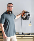 Person beside Heavy Duty Retractable Power Cord Reel 50ft 12AWG with lighted triple tap, mounted on a garage wall.
