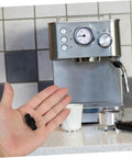 Person holding Heatproof Rubber Steam Wand Cover for Espresso Machine Pro Grade Insulation Sleeve near espresso machine.