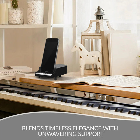 Sturdy Piano Phone Stand For Desk And Bedside Holder That Grips Up To 8 Cm Wide Phones, shown on piano beside decor and books.