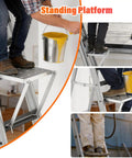 Heavy Duty Foldable Ladder Platform With Rock Solid Anti Slip Work Shelf Alloy Steel Step Attachment and Project Tray For Paint Gear Holds 400 Lbs Jobsite Ready, close-up of worker standing on ladder platform holding paint bucket.