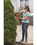 Woman using 16 Inch Hedge Trimmer With Dual Action Blade And Saw Blade 3.0 Amp Motor Delivers Less Vibration Cuts Branches Up To Five Eighths Inch Ideal For Hedging Shrubs And Bushes on a large shrub in a garden setting.
