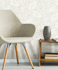 Living room with chair and table against beige Batik Tropical Leaf Peel And Stick Wallpaper Roll 20 Point 5 Inches Wide By 16 Point 5 Feet