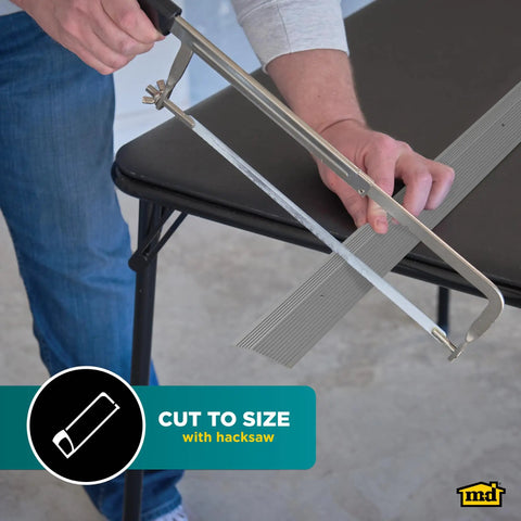 Person cutting Pewter Aluminum Carpet Trim 2 In By 36 In with saw on table, showing easy trim customization.