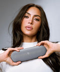 Woman holding All Day Battery Wireless Bluetooth Speaker With USB C Charging Punchy Bass Up To 24 Hours Of Battery Life IP67 Water Resistant Built In Mic Apple And Android Compatible Dark Gray Portable Party Speaker