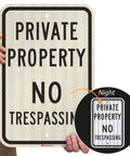 Premium Private Property No Trespassing Sign 12 X 18 Inches Reflective Aluminum Yard Board held by a person with night visibility feature.
