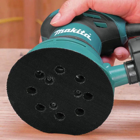 Person using five inch round backing pad with hook and loop for quick paper changes, eight hole design for easy dust extraction.